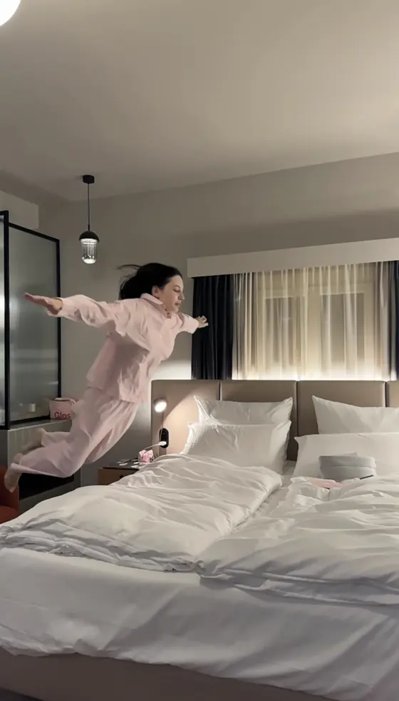 Me in pink pyjamas jumping towards the bed in the junior suite.