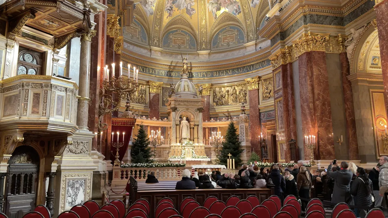 The basilica's altar area with candles, Christmas trees and visitors seated in rows.