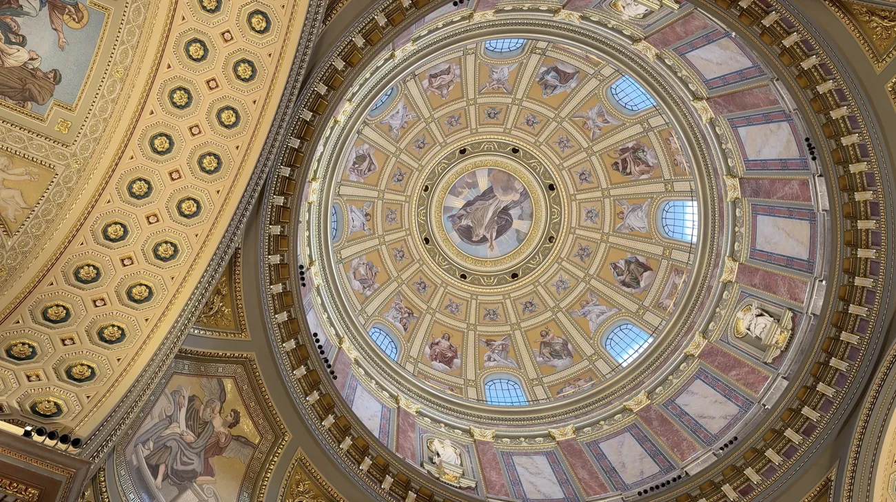 The decorated interior dome with gold patterns and round windows.
