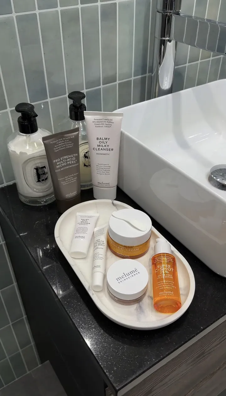 A tray of Melumé jars and tubes beside a bathroom sink.