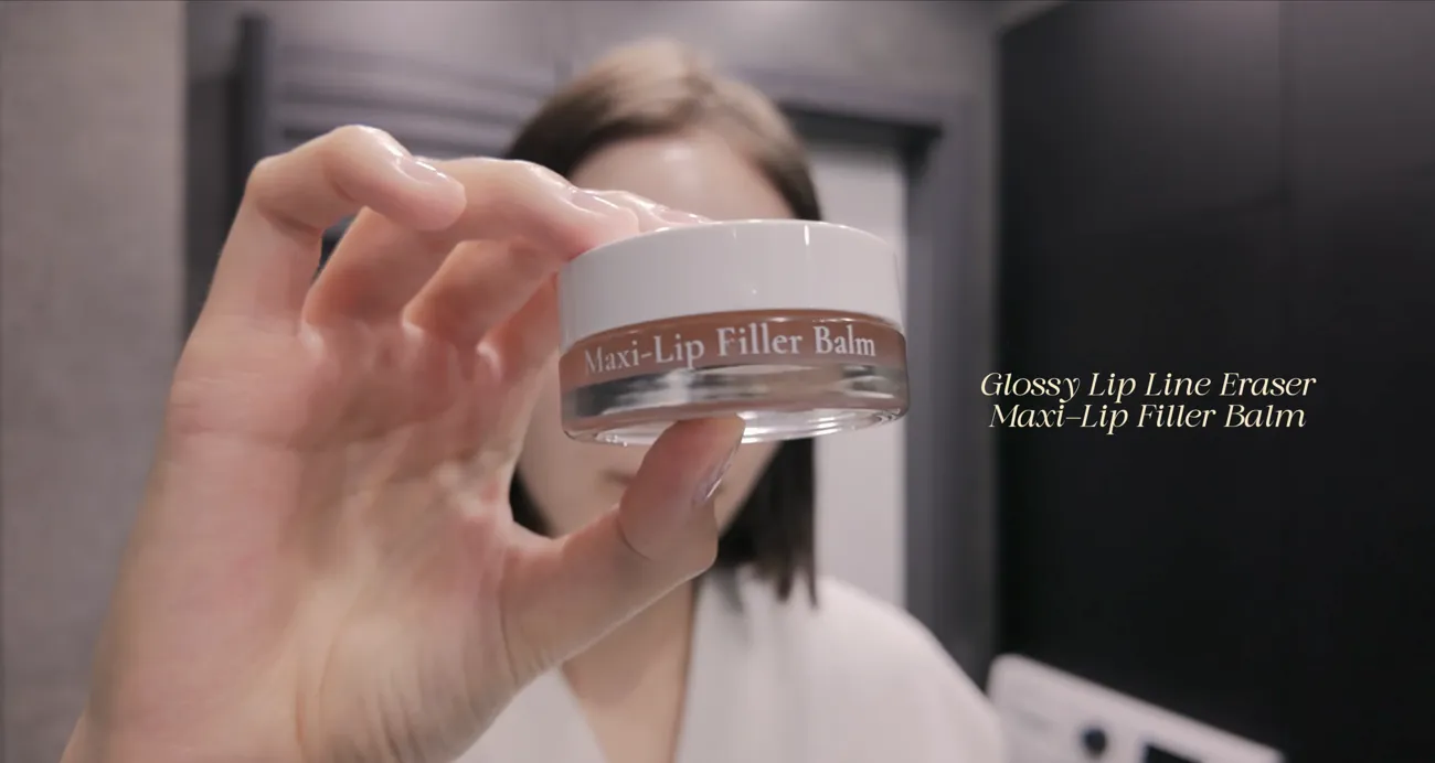 A hand holding a jar of Melumé Maxi-Lip Filler Balm.