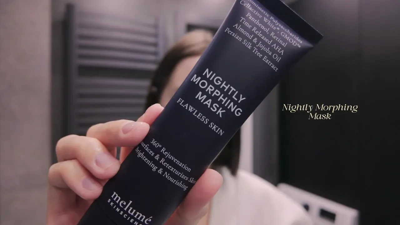 A hand holding a dark-blue tube of Melumé Nightly Morphing Mask.