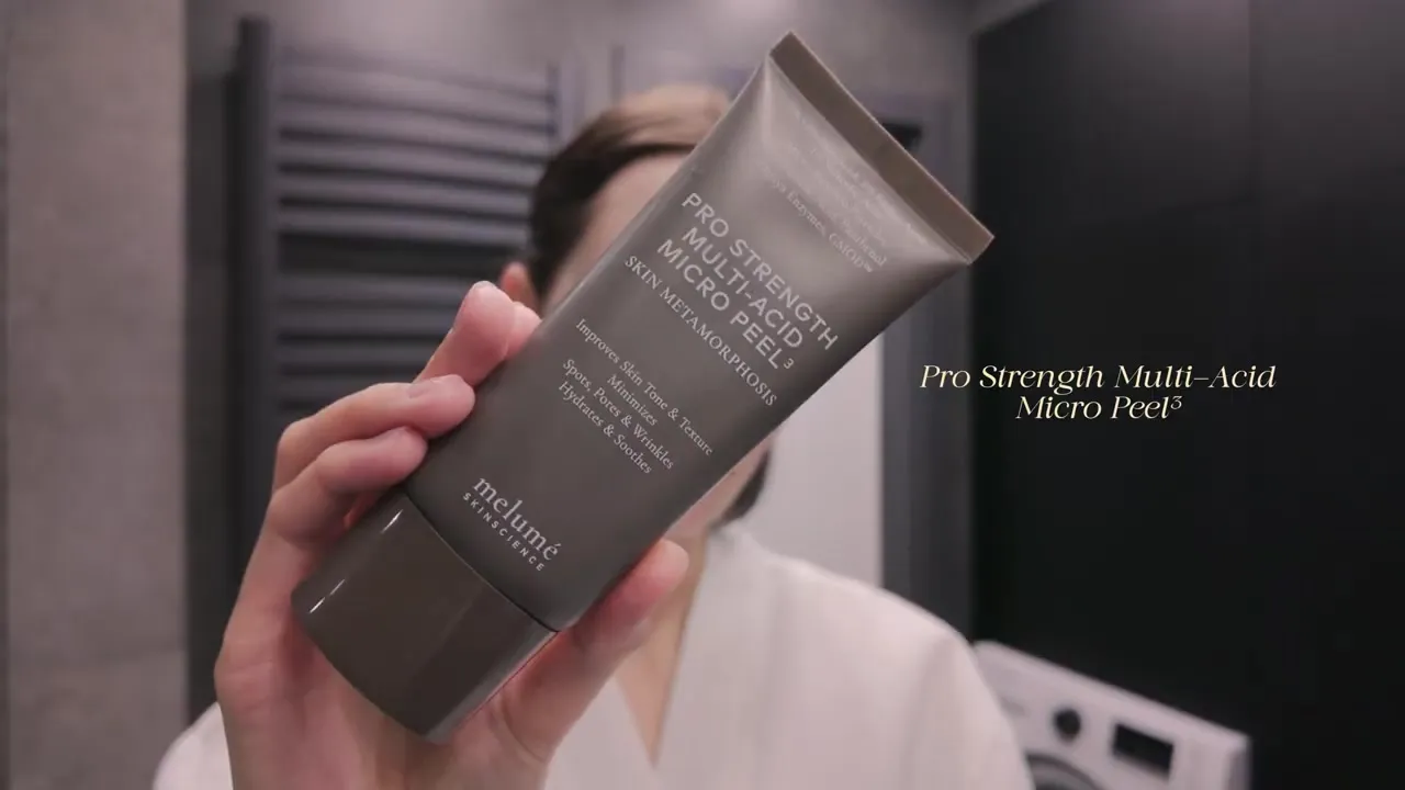A hand holding a grey tube of Melumé Pro Strength Multi-Acid Micro Peel.