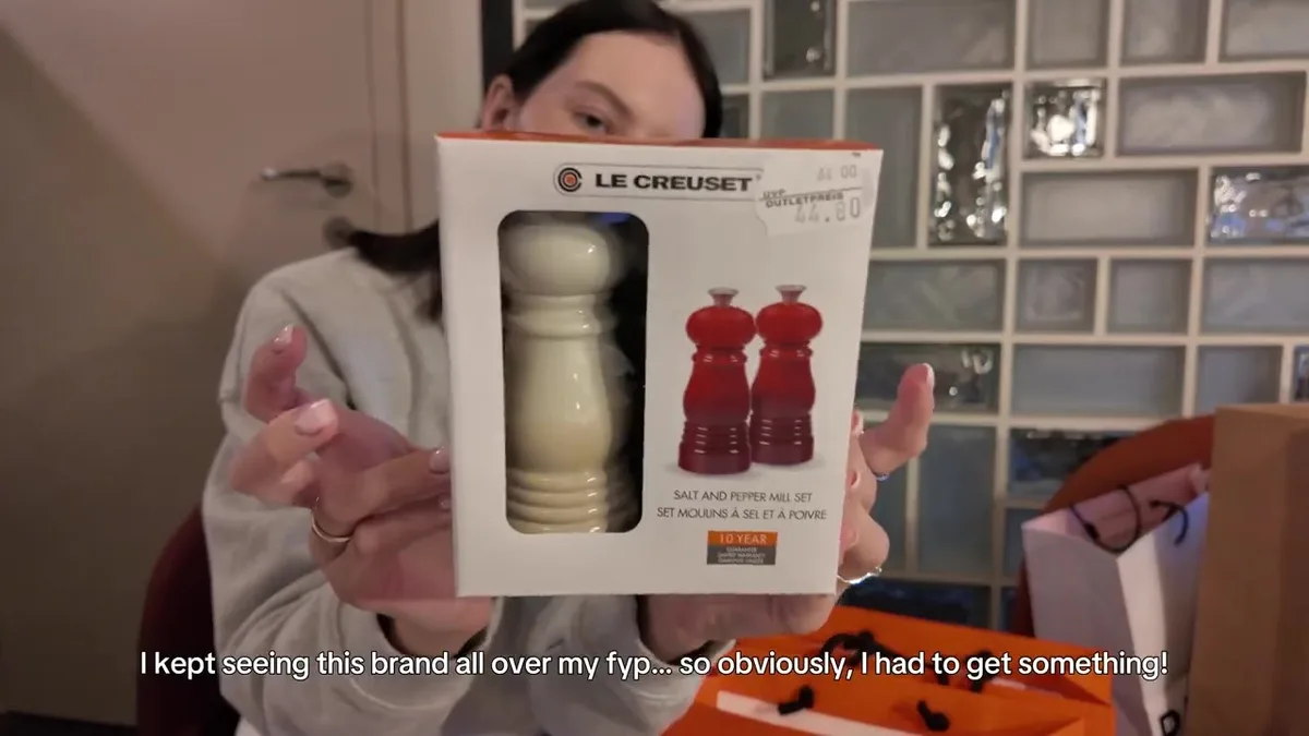 Me holding a boxed Le Creuset mill set with a visible 44.80 outlet-price label.