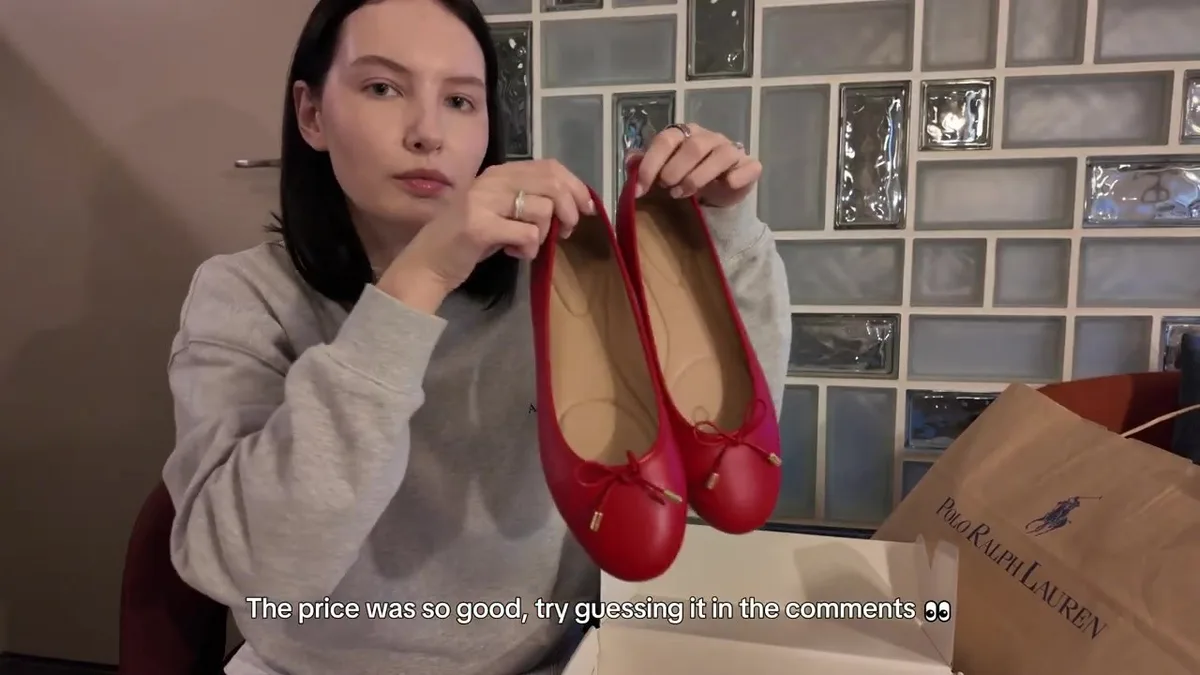 Me holding red ballet flats with rounded toes, bows and gold-coloured details.