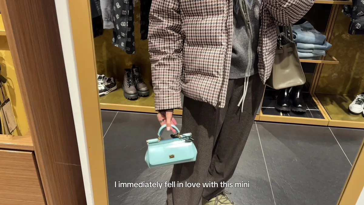 Me holding a small turquoise Dolce & Gabbana top-handle bag in front of a mirror.