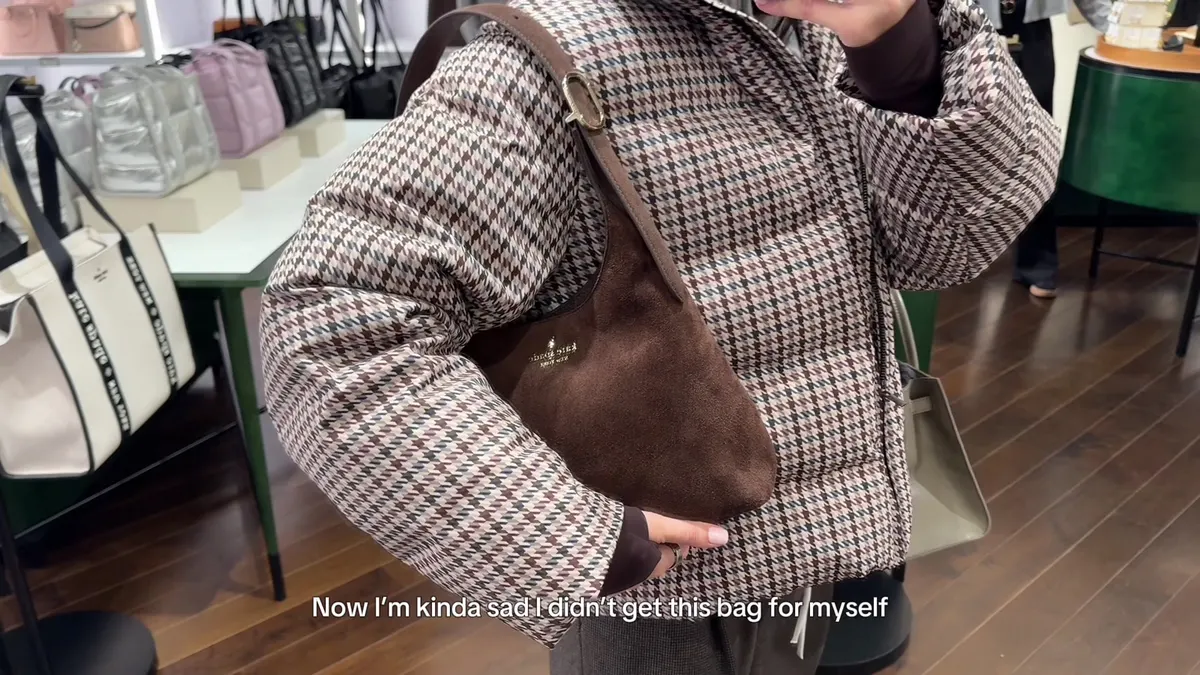 Me holding a brown suede Kate Spade shoulder bag in front of a mirror.