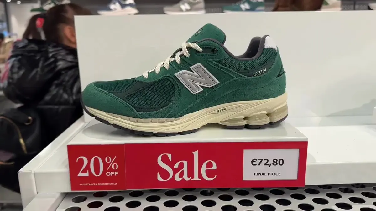 Green New Balance 2002R above a sale sign showing €72.80 final price and 20% off selected styles.