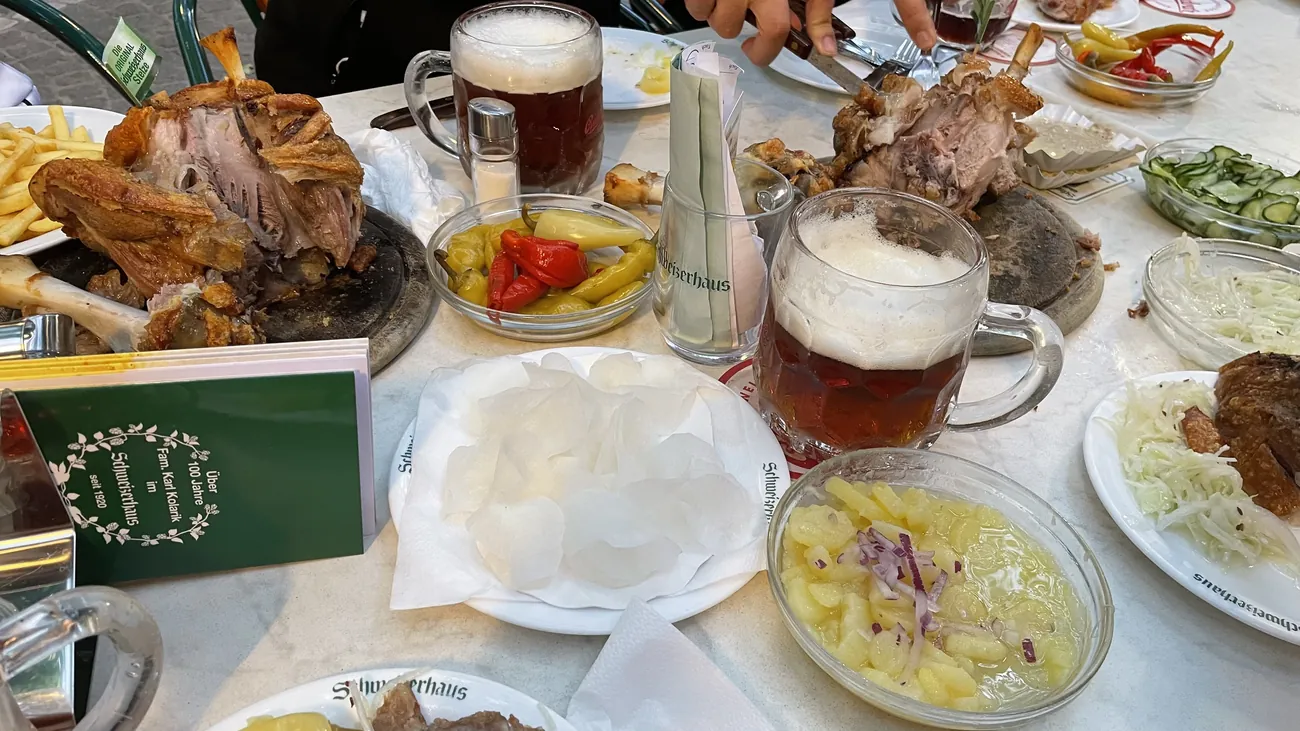 A shared Schweizerhaus table with roast pork, beer and side dishes
