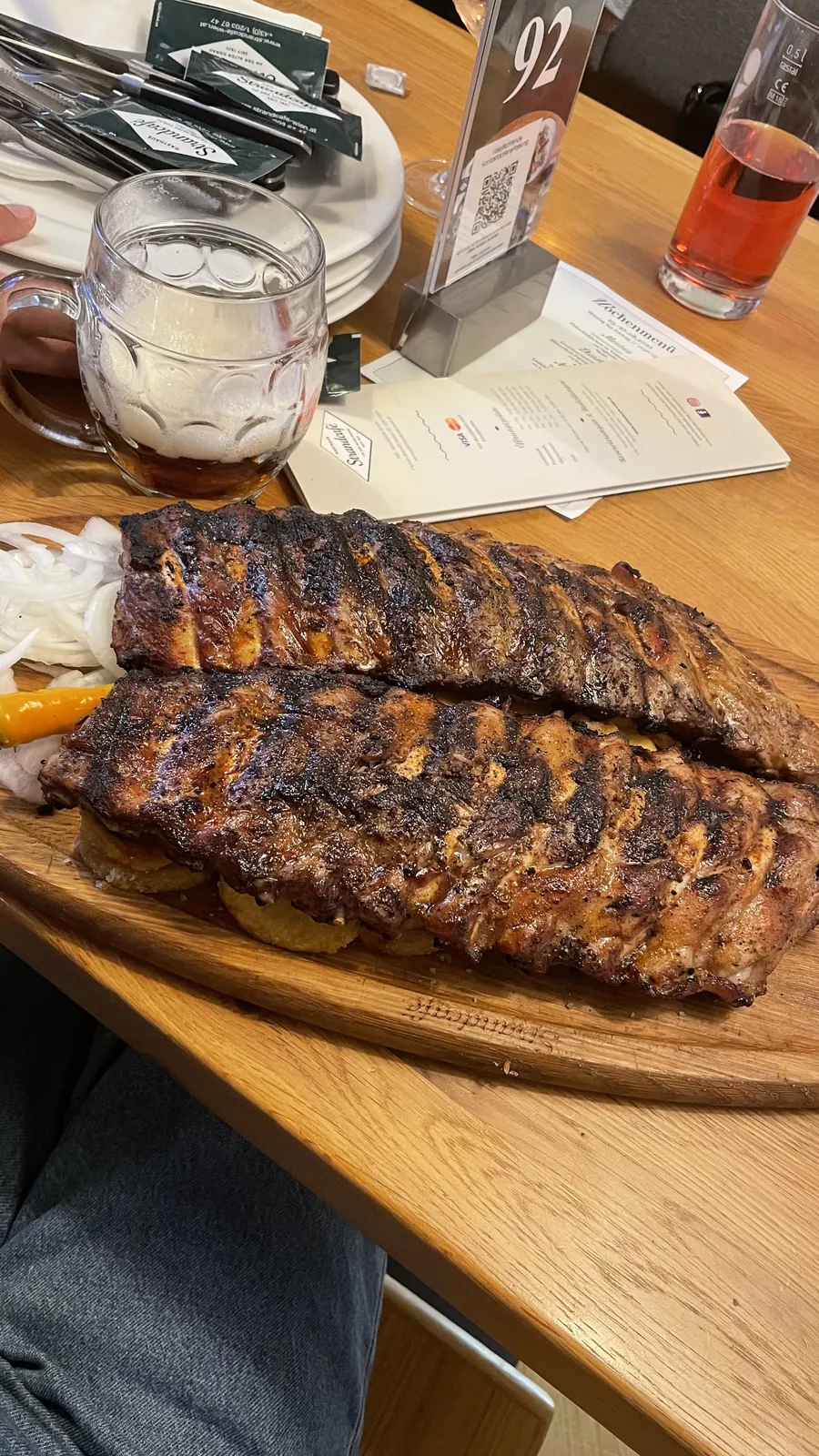 Grilled ribs on a wooden board beside a beer mug at Strandcafé