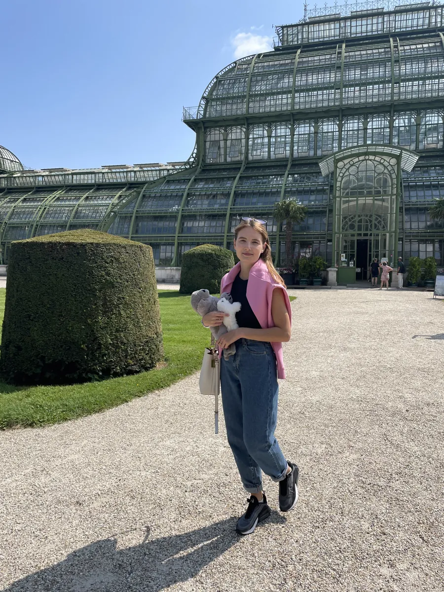 Me holding a soft toy outside a large glasshouse